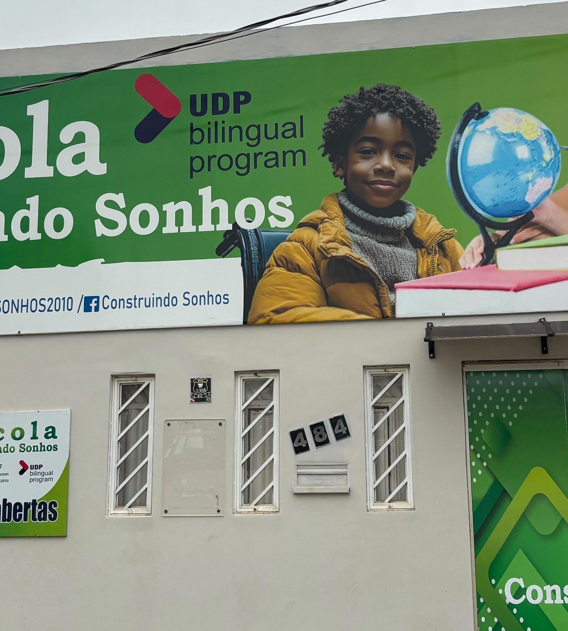 Fachada da Escola Construindo Sonhos, com faixa verde do programa bilíngue
